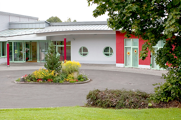 Außenansicht der Wilhelm-Albrecht-Schule: Modernes Gebäude mit Grünfläche im Vordergrund.